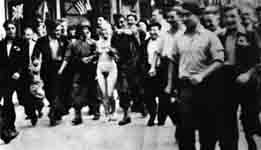 Une femme nue emmenée par des soldats français entourée de résistants.  - 1945