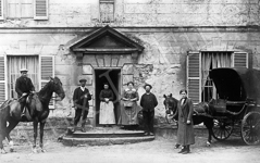 Une famille bourgeoise pose devant l'entrée de leur château avec leurs employés.  - 1900