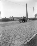 Laitier et laiti�re en costume local avec voiture � bras de laitier sur une route pav�e dans un paysage industriel  - Nord-Pas-de-Calais (59)  - 1900