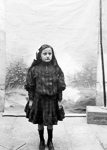 Une petite fille devant un fond peint, dans un atelier de photographie improvis  - 1900