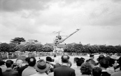Un h�licopt�re style alouette att�rit au milieu d'une foule  - 1960