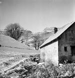 Paysage de montagne sous la neige avec une maison en pierre.  - 1945